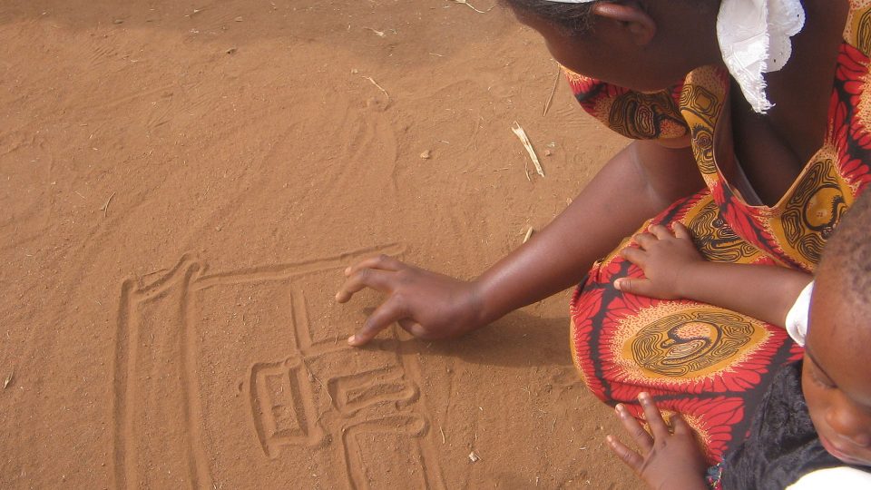 Child drawing in sand