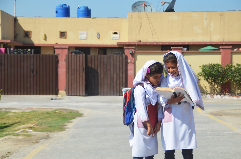 Two schoolgirls reading outside a Reall house