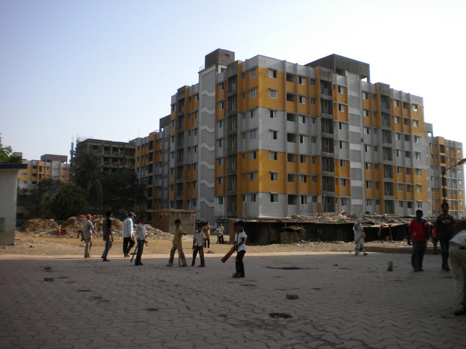 Boys playing cricket in front of high-rise living accomodation