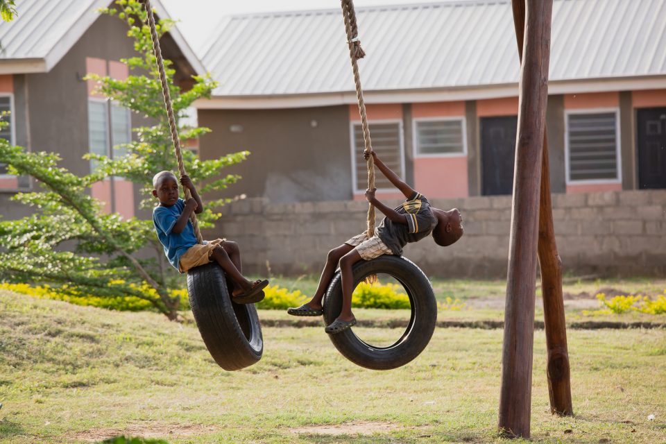 Children playing on swings against the backdrop of Reall house in Abuja, Nigeria