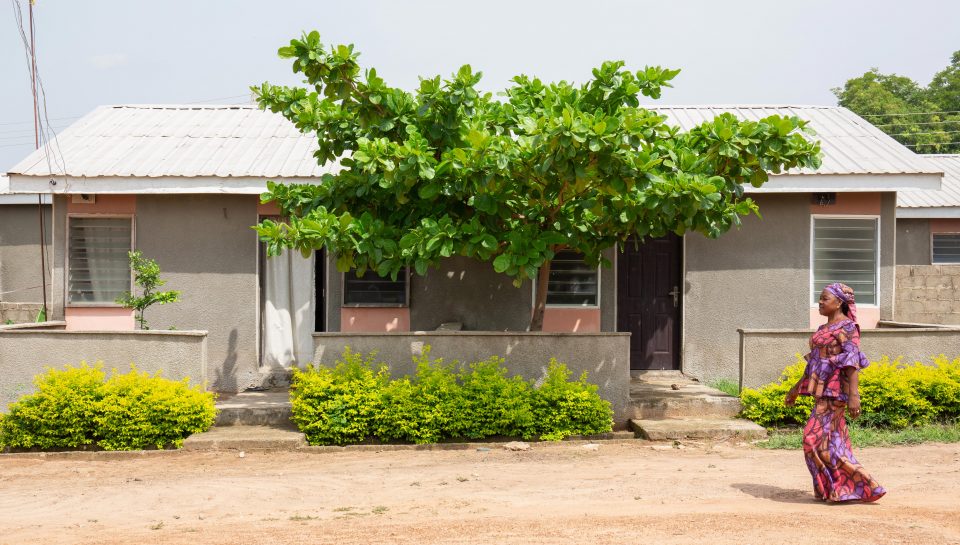 Lady walking past Reall project house in Nigeria